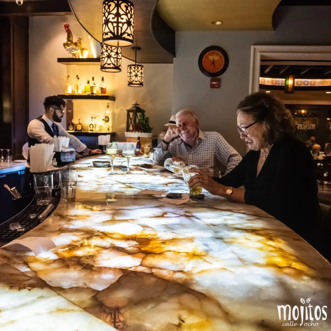 Bartender serving guests at the backlit onyx bar top at Mojitos Calle 8, Cuban restaurant on Calle Ocho, Miami