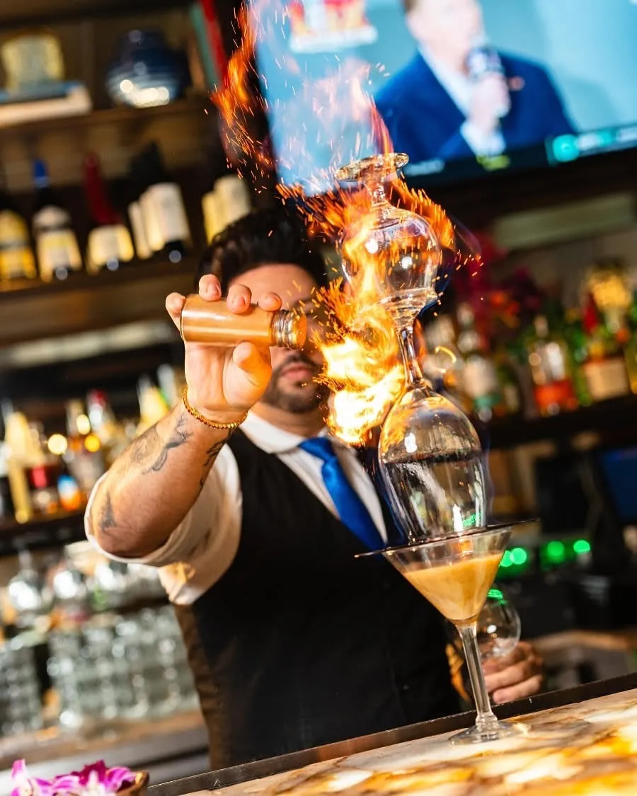 Bartender sirviendo un espresso martini flameado con chispas y fuego sobre la copa en la barra de Mojitos Calle 8, restaurante cubano en Miami