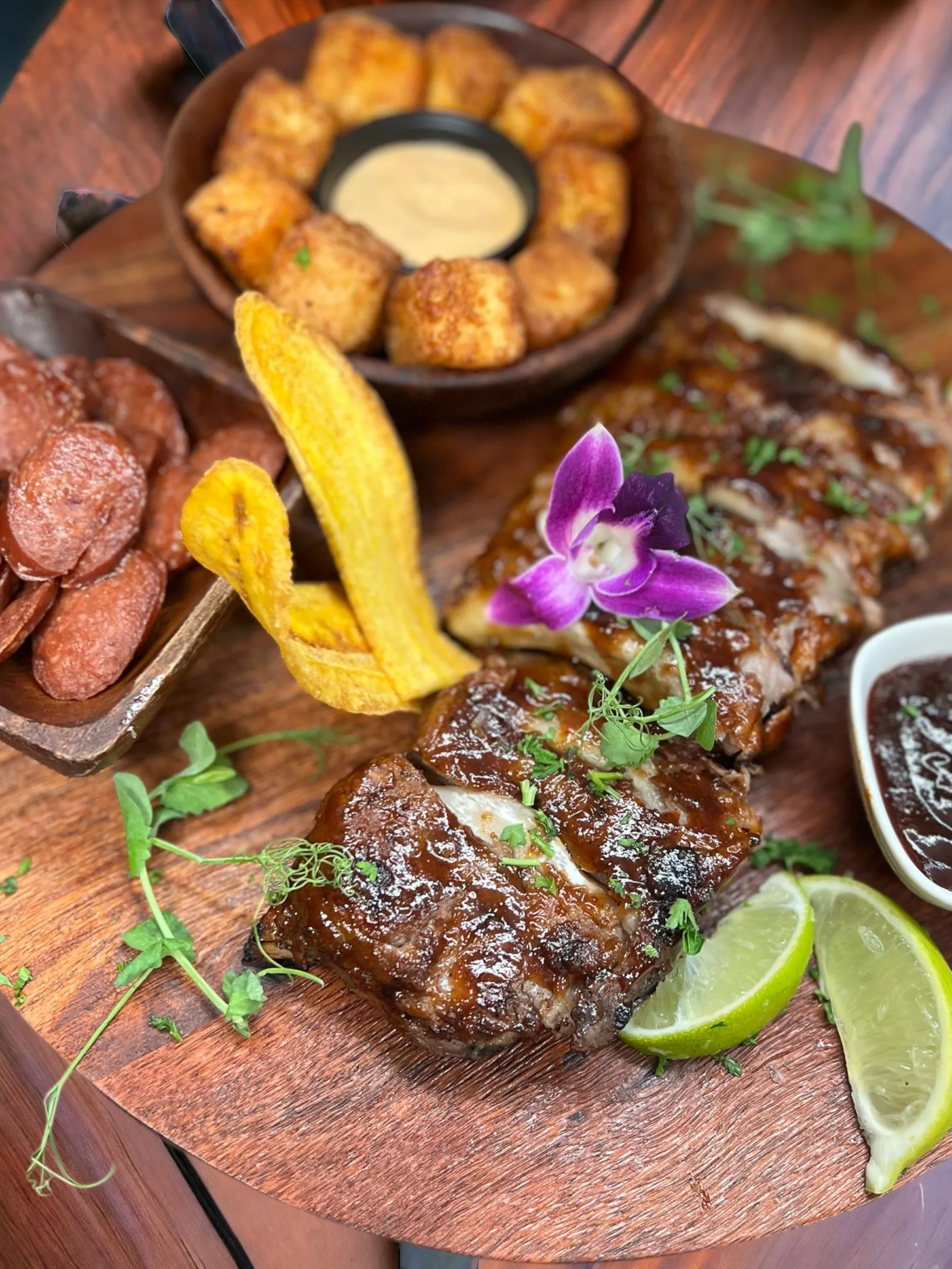 Costillas de cerdo a la barbacoa en tabla de madera con chicharrones, rodajas de chorizo a la parrilla, mariquitas de plátano, limón y salsas en Mojitos Calle 8, restaurante cubano en Miami