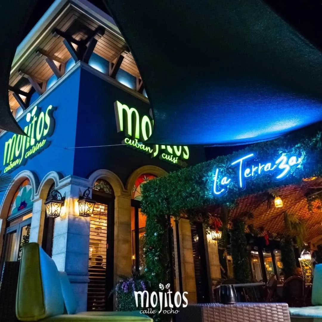 Night view of the blue corner facade with the La Terraza neon sign and covered patio at Mojitos Calle 8, Calle Ocho Miami