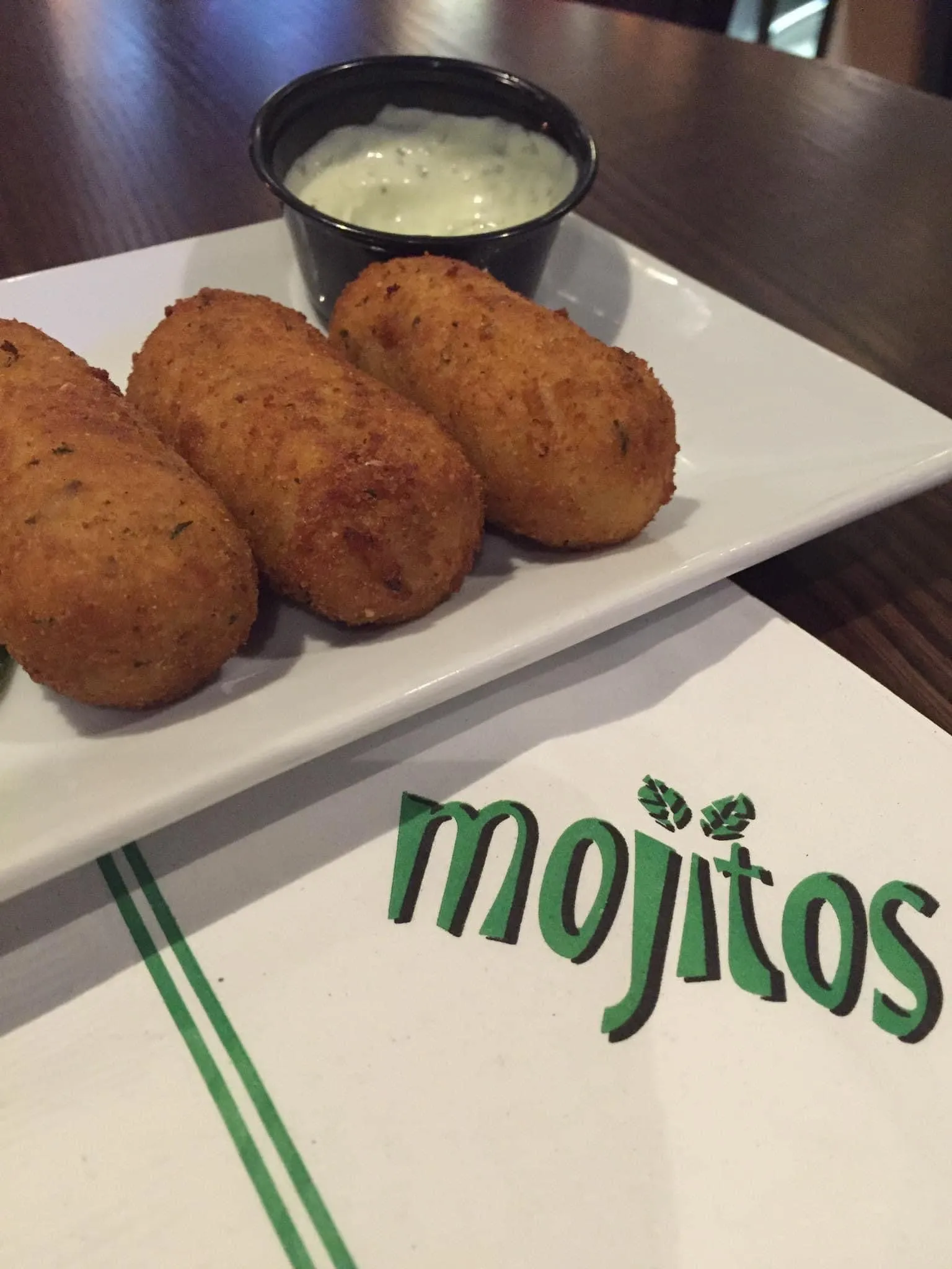 Croquetas de jamón cubanas doradas servidas con salsa cremosa de cilantro en un plato blanco en Mojitos Calle 8 en Miami