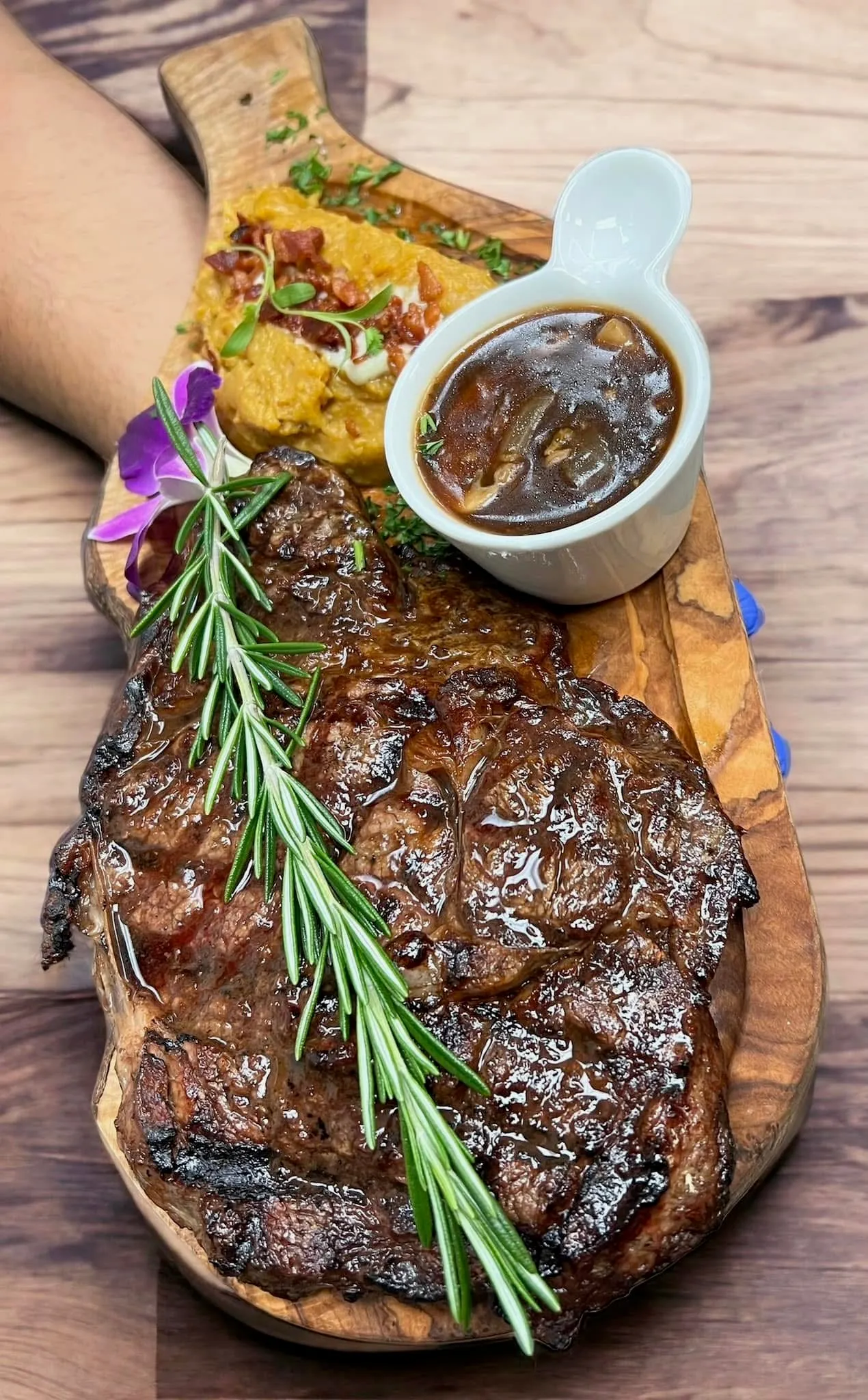 Ribeye a la parrilla sobre tabla de madera con romero, salsa de champiñones y fufú de plátano con tocineta en Mojitos Calle 8, restaurante cubano en Miami