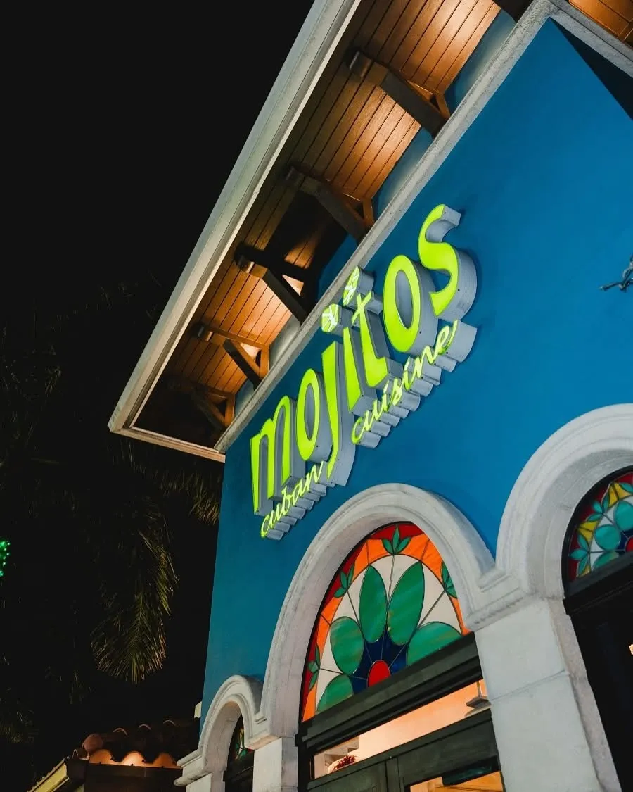 Illuminated green Mojitos Cuban Cuisine sign on the blue facade at night, Mojitos Calle 8 on Calle Ocho, Miami