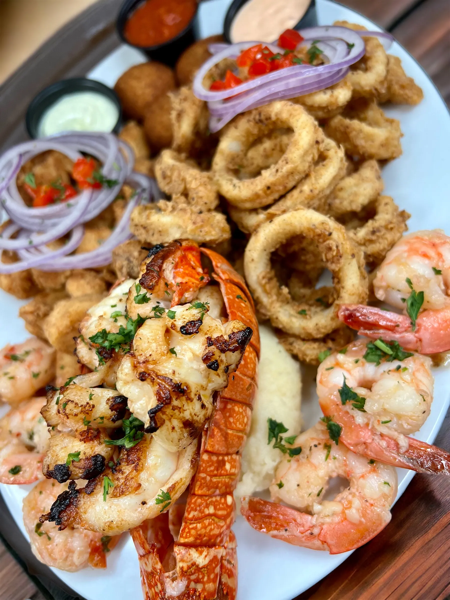 Mariscada con cola de langosta a la parrilla, camarones al ajillo, calamares fritos, bocaditos de pescado y puré de papas con salsas en Mojitos Calle 8, restaurante cubano en Miami