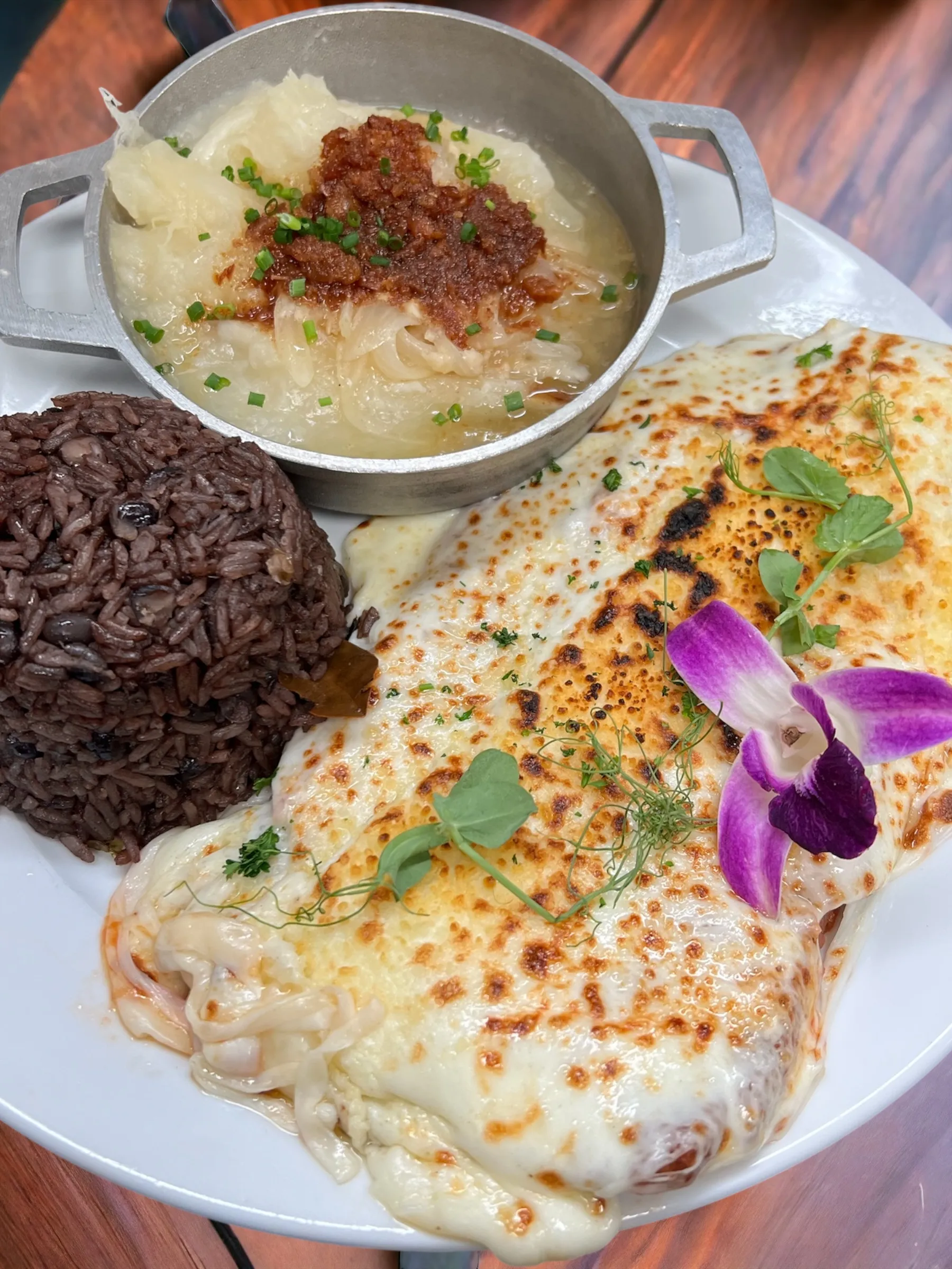 Pechuga de pollo gratinada con queso derretido servida con congrí y una cazuela de yuca con mojo, ajo y cebollín en Mojitos Calle 8, restaurante cubano en Miami