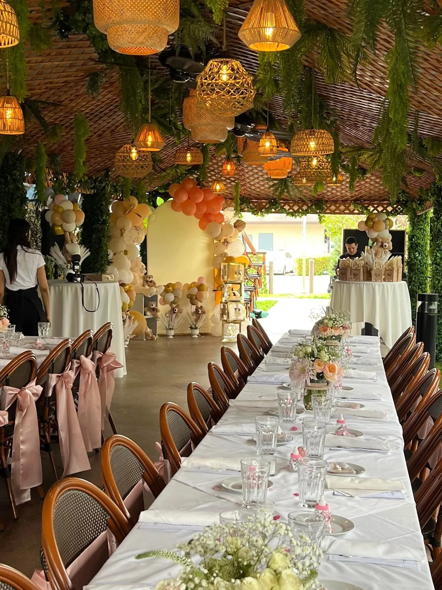 Private baby shower event with long banquet tables, balloon arch and florals set up on the terraza at Mojitos Calle 8, Miami