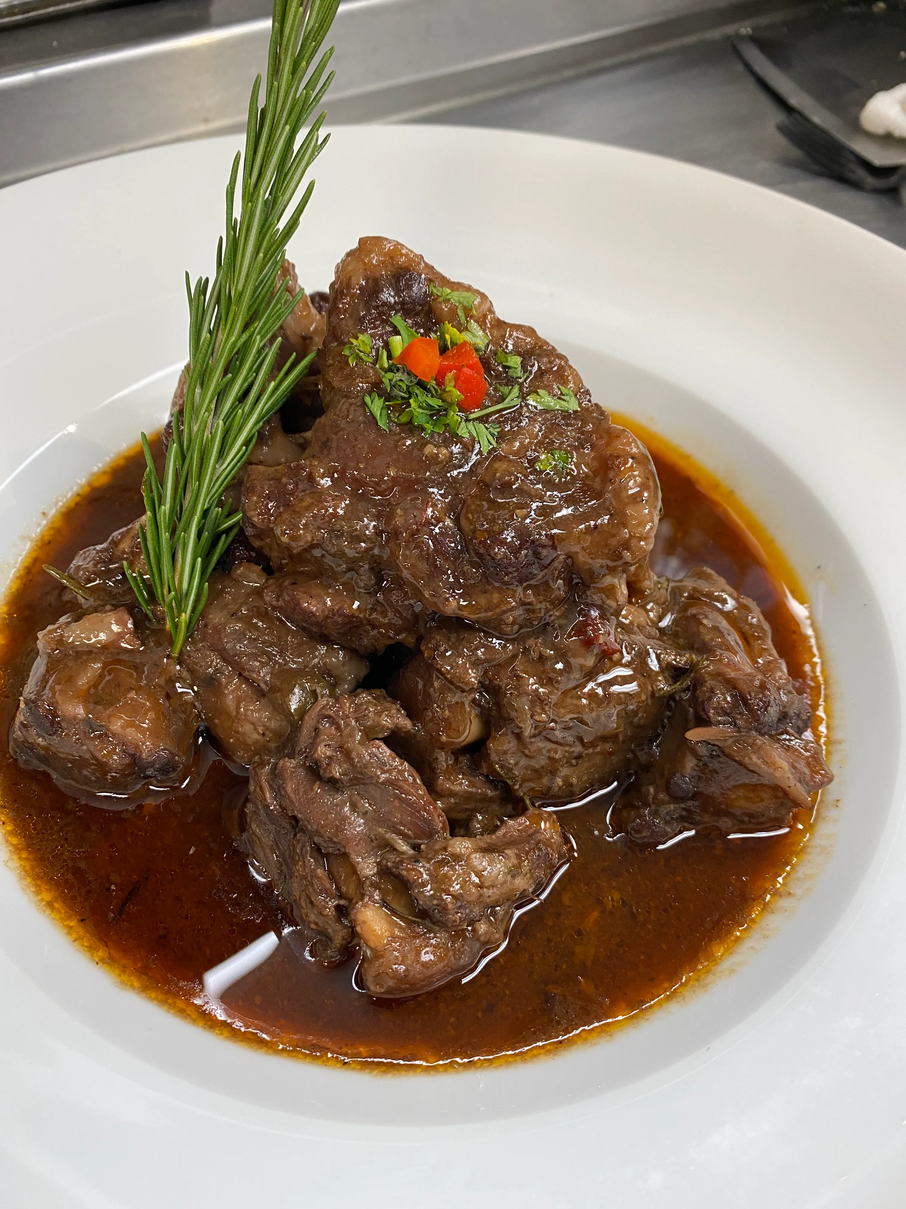 Rabo encendido, rabo de res cubano guisado en salsa criolla de vino tinto y decorado con romero, en Mojitos Calle 8, restaurante cubano en Miami